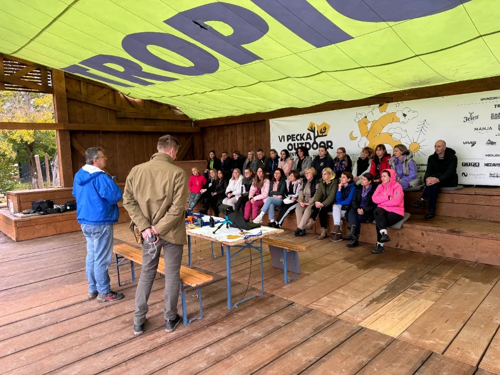 Vanjske radio-demonstracije pod nadstrešnicom sa stolom opreme i učesnicima